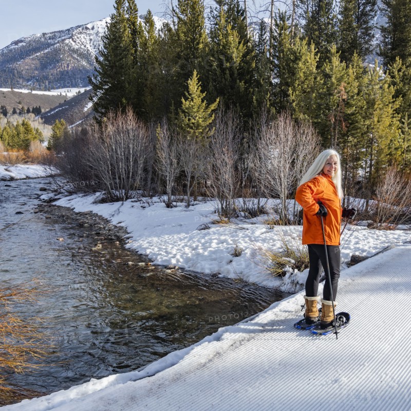 Senior blonde woman snowshoeing in snow covered landscape