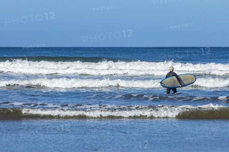 Senior surfer carrying surfboard