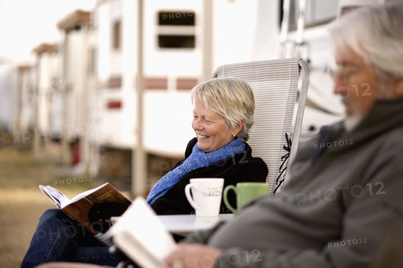 Senior couple reading book outside mobile home