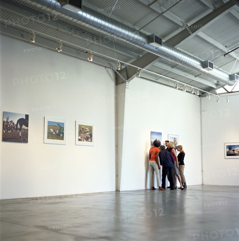Group of people looking closely at photograph in art gallery