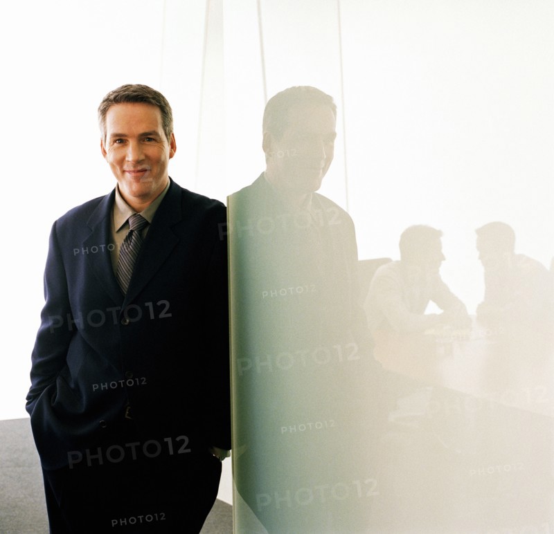 Portrait of business executive leaning against glass wall