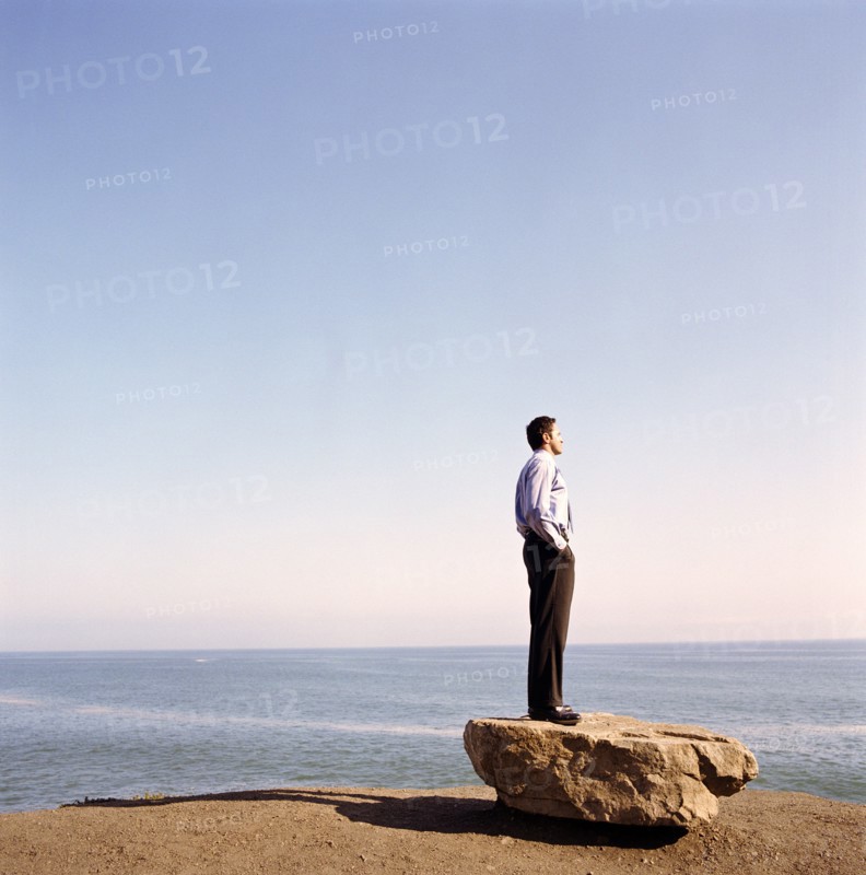 USA, California, Point Mugu, Businessman standing on rock on beach