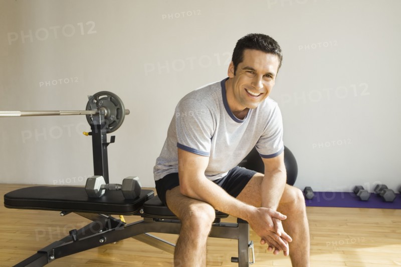 Portrait of man sitting on weight bench