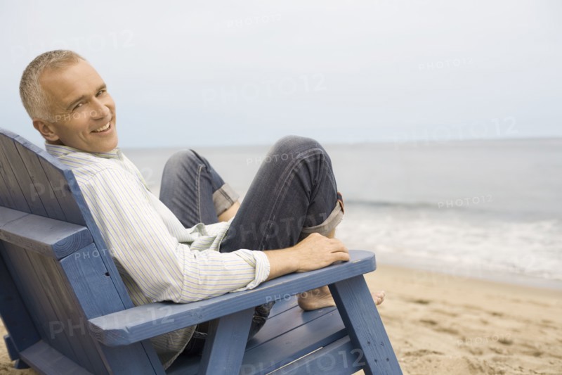 Portrait of mature man sitting in chair on beach