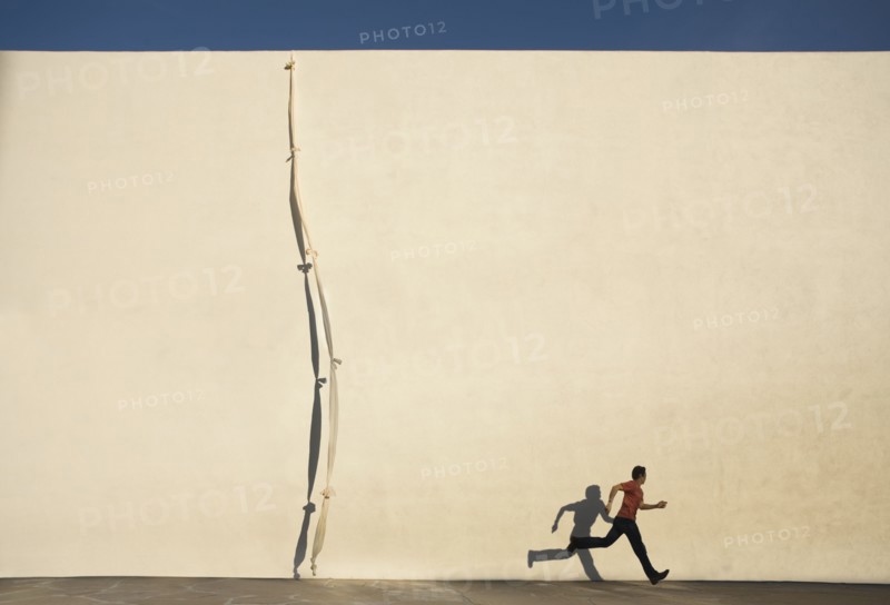 Man escaping by climbing rope over wall