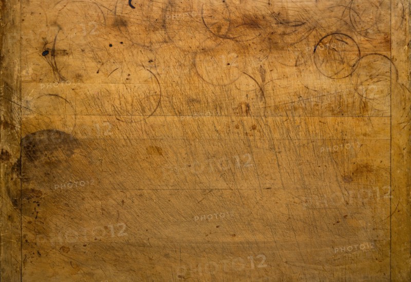 Close-up of worn antique cutting board with knife cut marks and glass rings