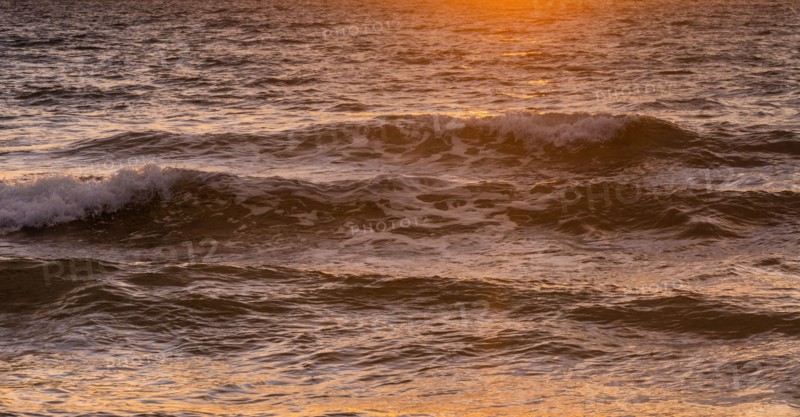 Close-up of ocean waves washing beach at sunrise