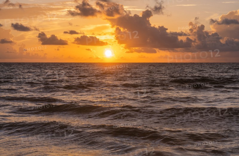 Golden clouds over ocean at sunrise