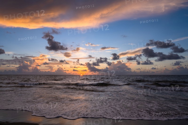 Dramatic sunrise sky above ocean and beach