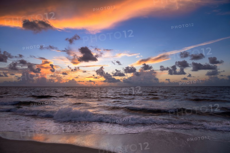 Dramatic sunrise sky above ocean and beach