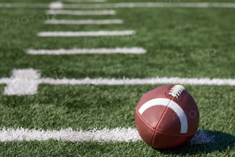 American football ball at yard line markers on playing field