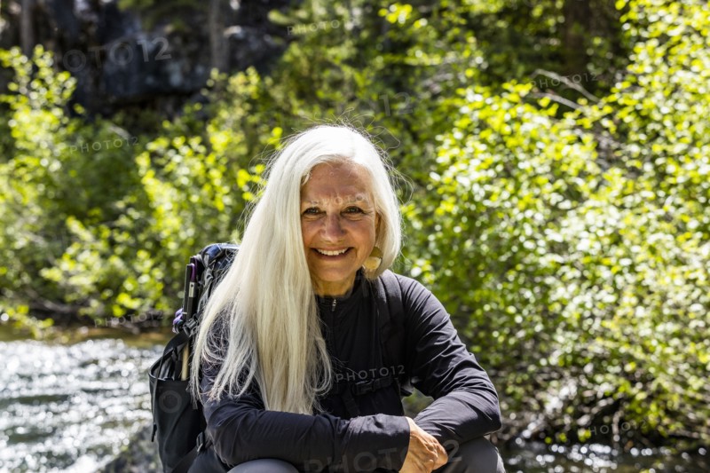 Senior blonde woman resting by rushing stream near Sun Valley