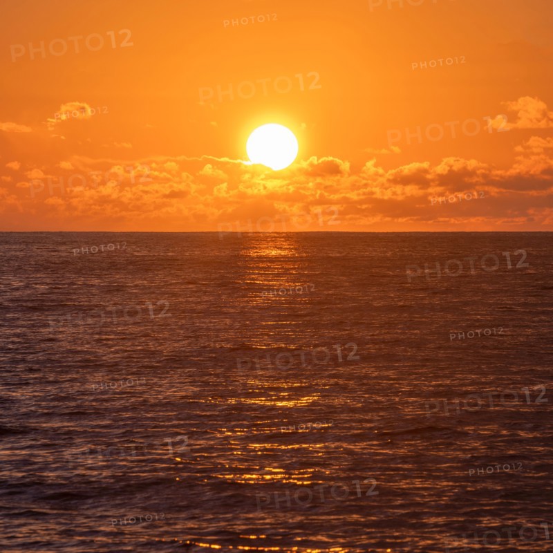 Sun rising above calm ocean