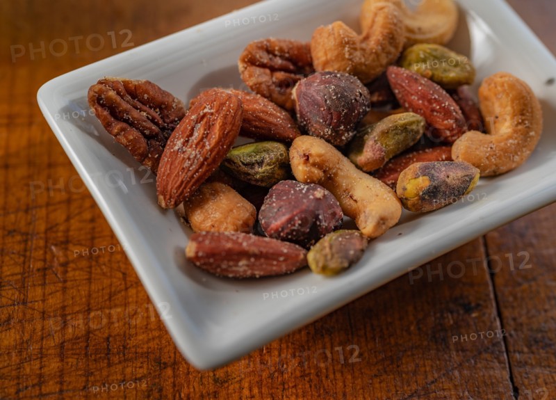 Close-up of small dish of assorted nuts on wooden table