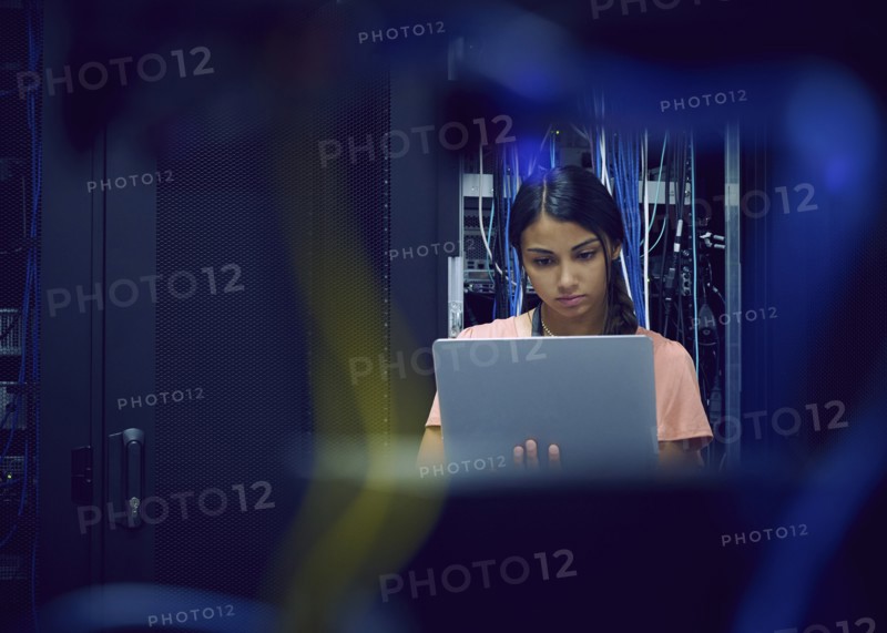 Female technician using laptop in server room