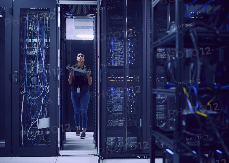 Female technician carrying hard drive in server room