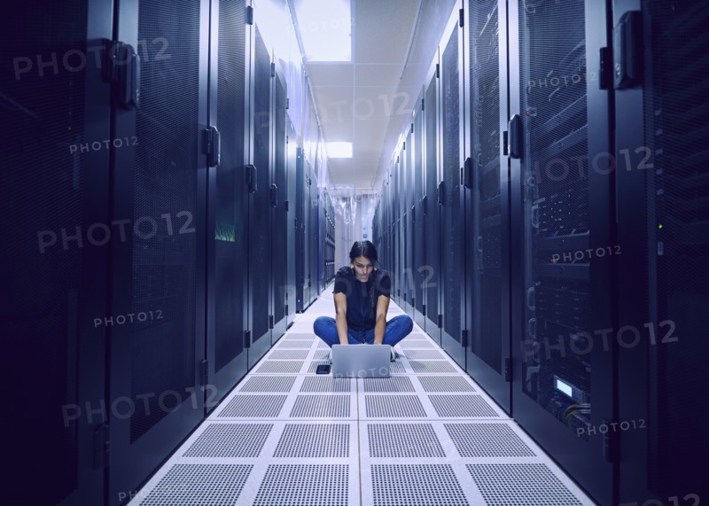 Female technician using laptop on floor in server room
