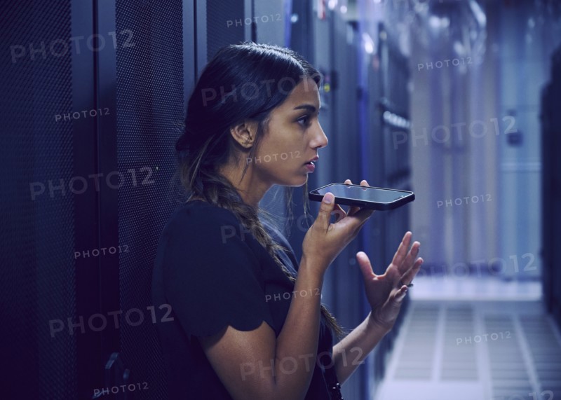 Female technician using smart phone in server room