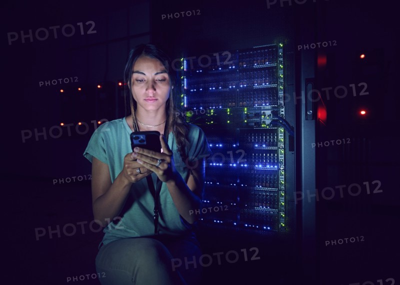 Technician using smart phone in server room