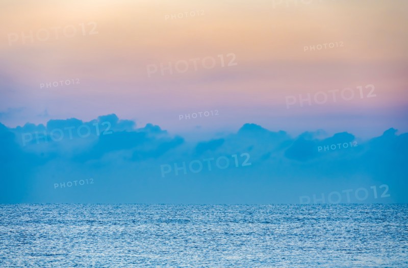 Clouds above calm ocean at sunrise