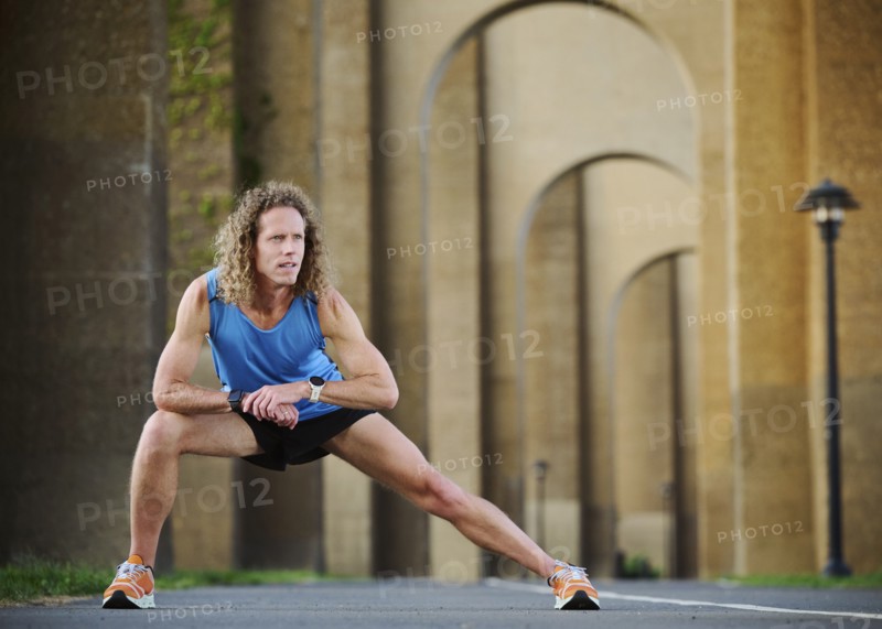 Runner stretching under bridge