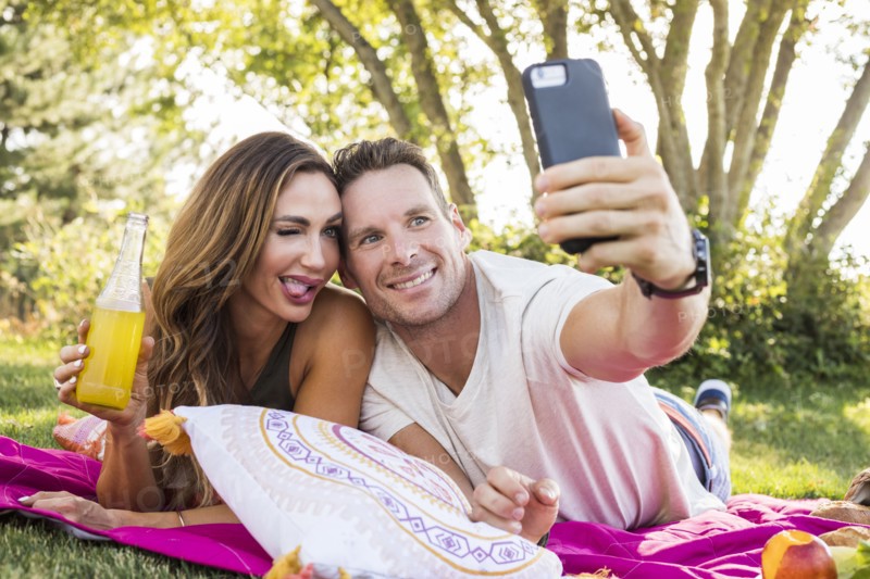 Smiling couple taking selfie in park