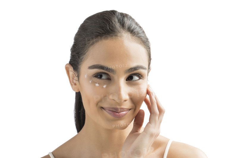 Portrait of smiling young woman applying face cream