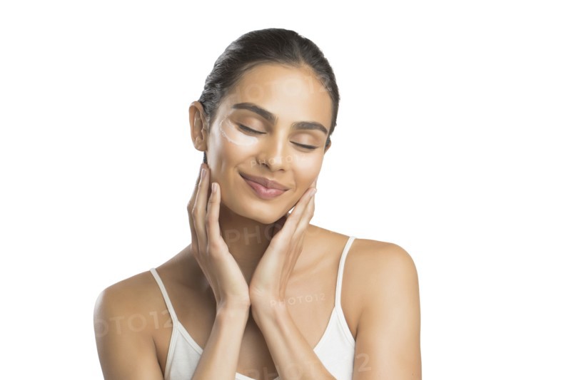 Portrait of smiling young woman applying face cream