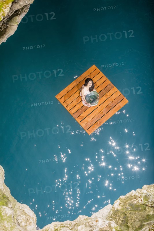Aerial view of woman sitting on wooden raft