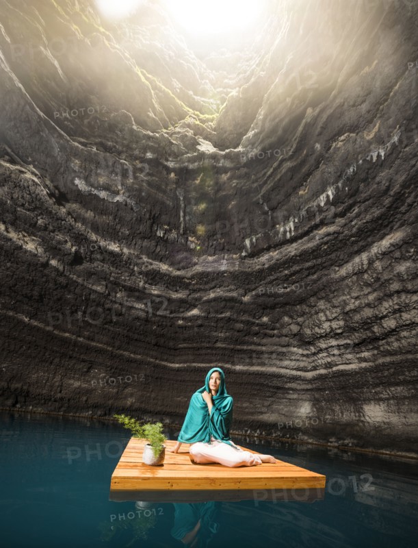 Woman sitting on wooden raft in cenote