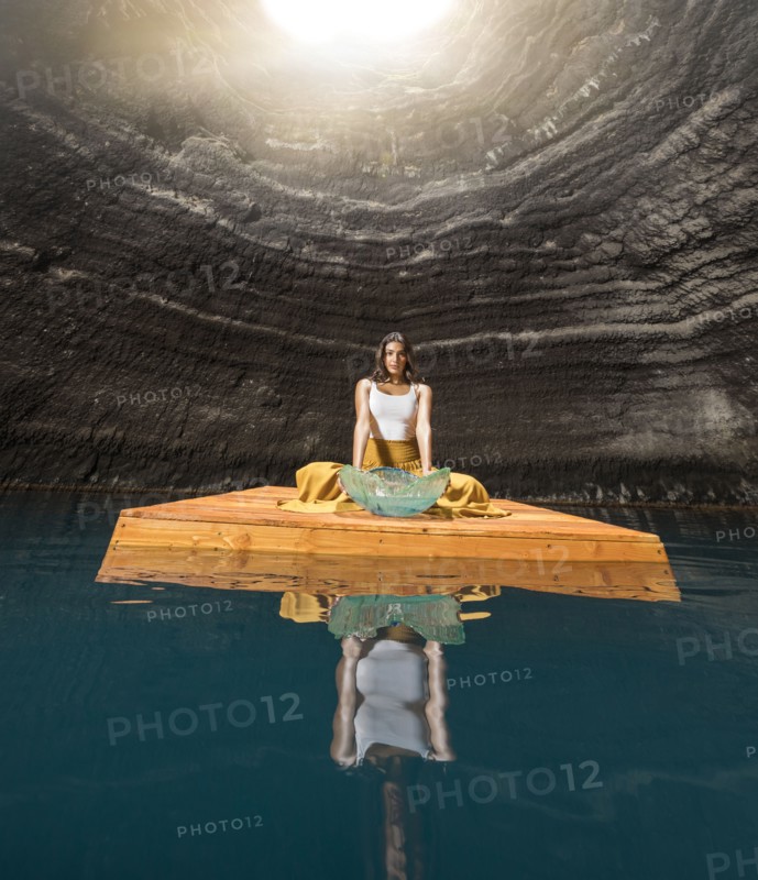 Woman sitting on wooden raft in cenote
