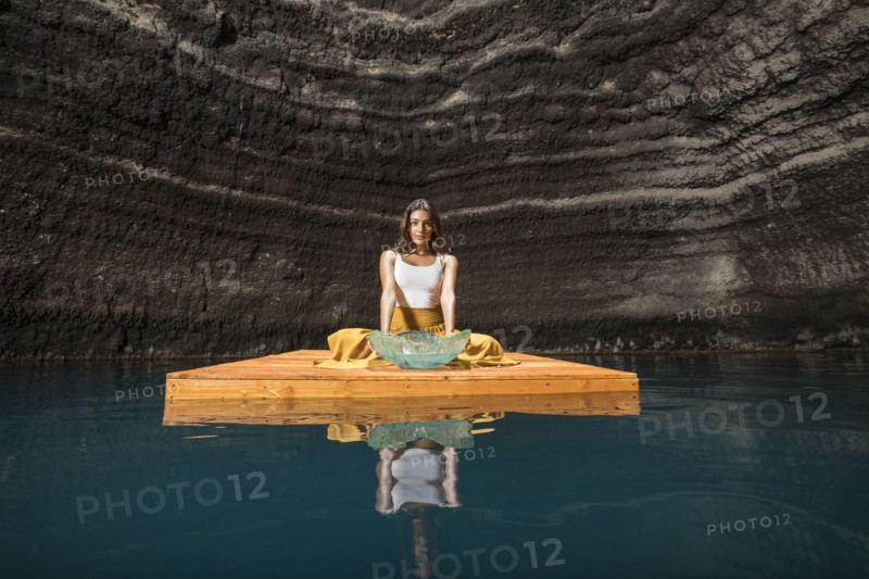 Woman sitting on wooden raft in cenote