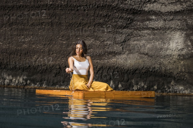 Woman sitting on wooden raft in cenote