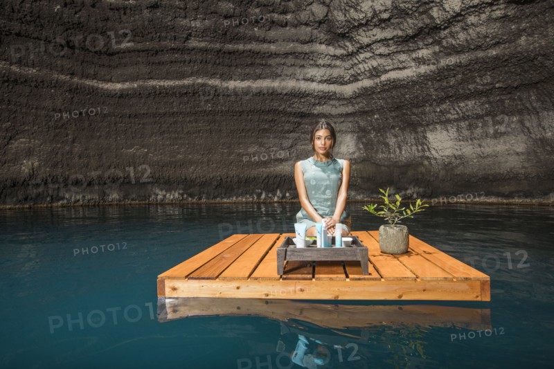 Beautiful woman kneeling on wooden raft on pond