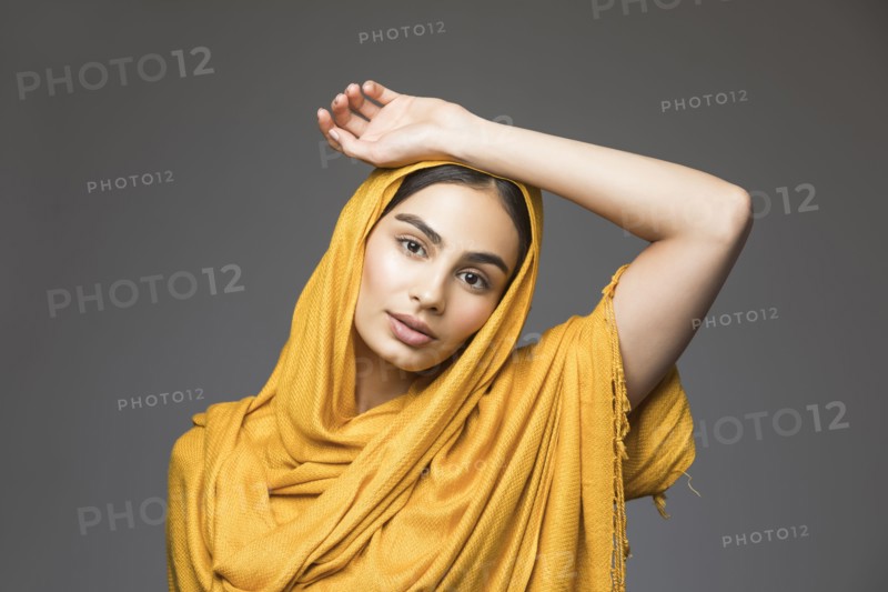 Studio portrait of beautiful woman wearing gold headscarf
