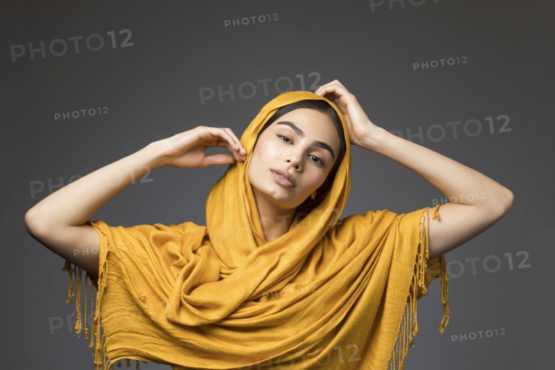 Studio portrait of beautiful woman wearing gold headscarf
