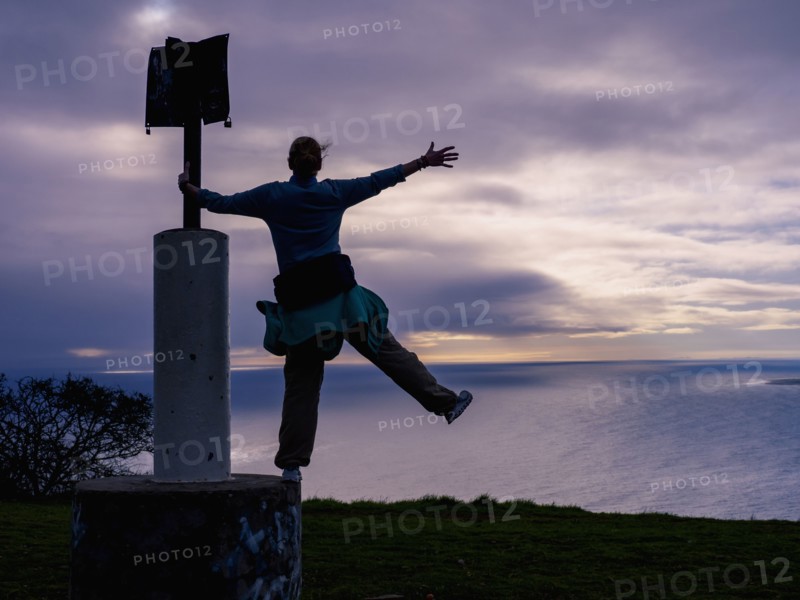 Woman standing on sign post on sea coast
