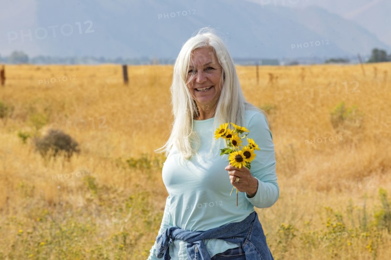 Portrait of senior woman holding bunch of sunflowers