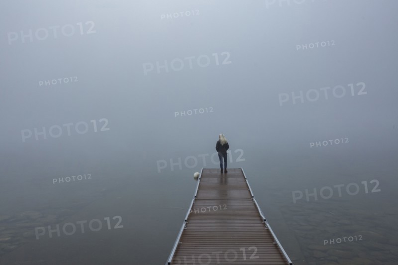 Back view of senior woman standing on jetty in morning