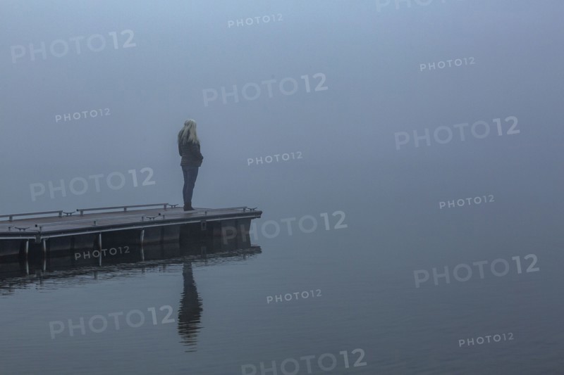 Senior woman standing on jetty in foggy morning