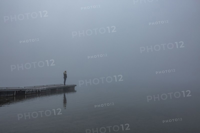 Woman standing on jetty in morning by lake