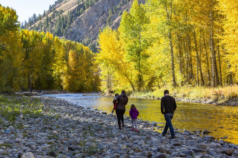 Family admires fall along river in autumn