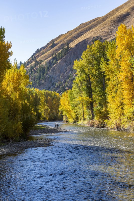 Distant view of family admires fall along river in autumn