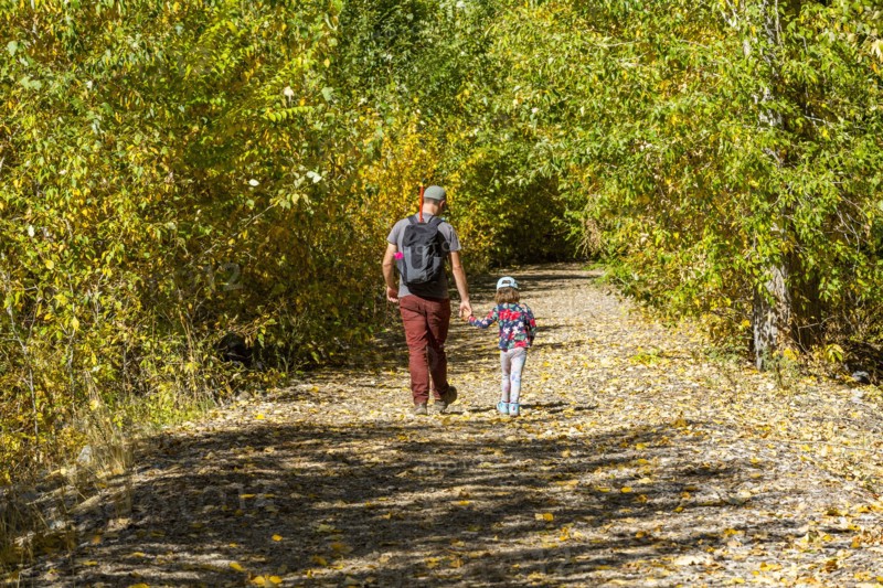 Father and daughter walk rural path in fall