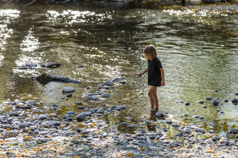Girl exploring river shallows in summer