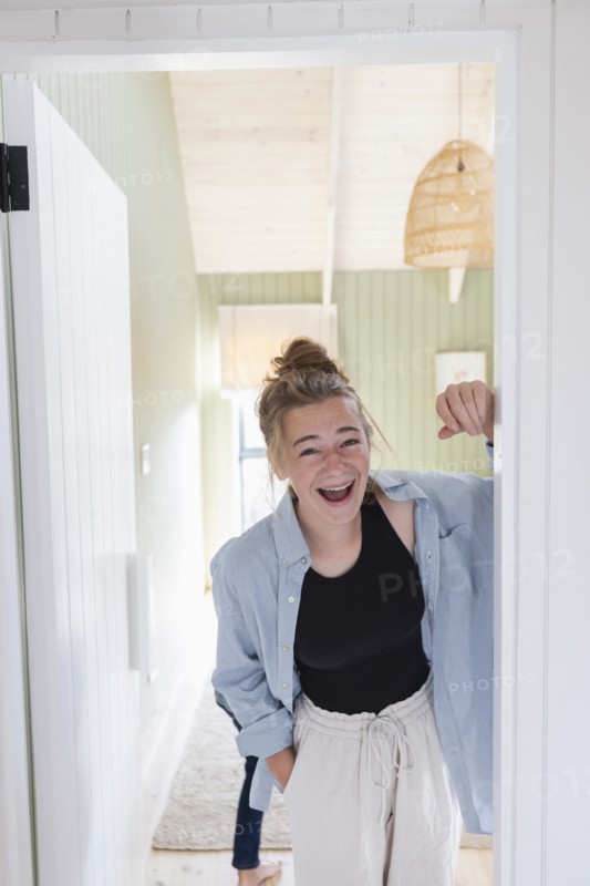 Portrait of teenage girl standing in doorway and laughing