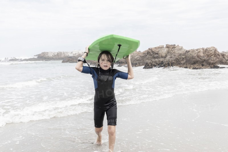 Boy carrying bodyboard on Voelklip beach