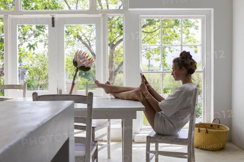 Teenage girl using smart phone in dining room