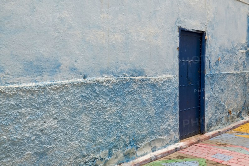 Colorful blue walls and old door in alleyway in medina