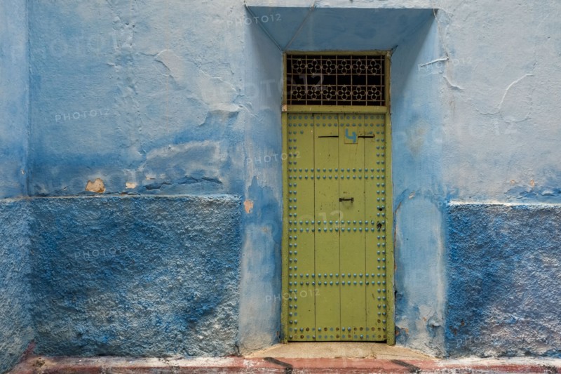 Colorful blue walls and old door in alleyway in medina